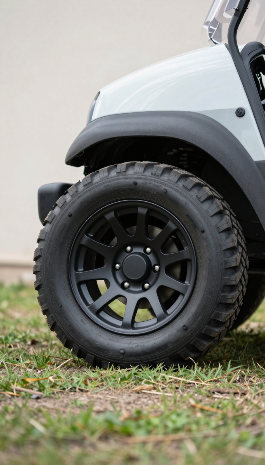 Matte Black Custom Golf Cart Wheels With Aggressive Off-Road Tires Positioned At Dynamic Angle On Grassy Terrain